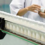 Glass bottles on the conveyor belt. Woman controls product on the background